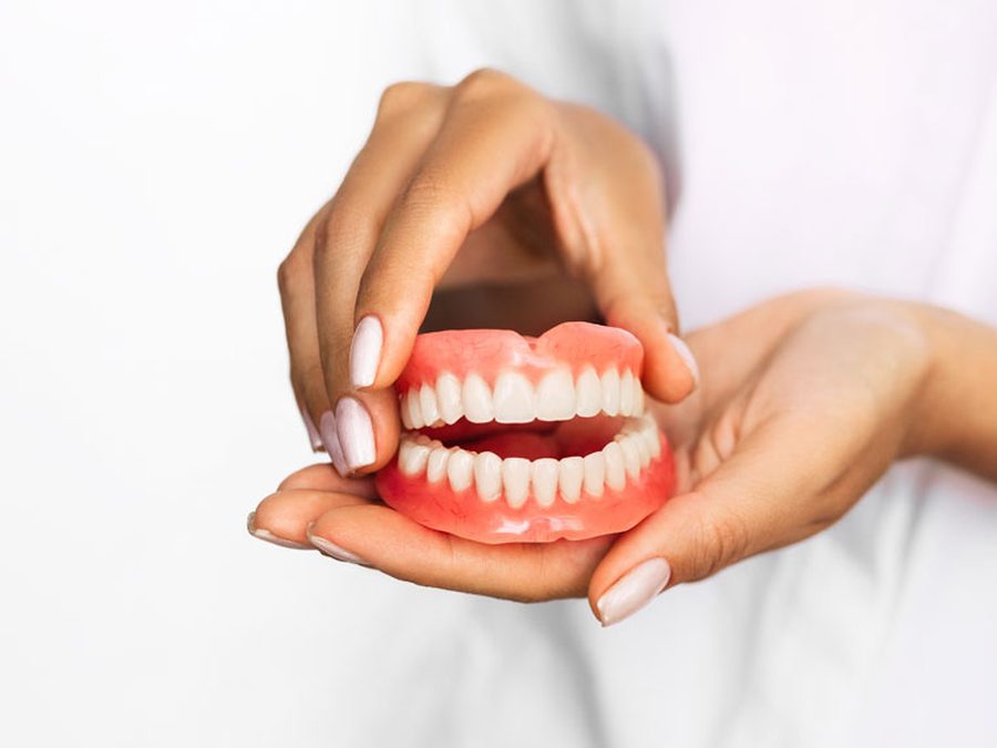 Manos sujetando una dentadura completa